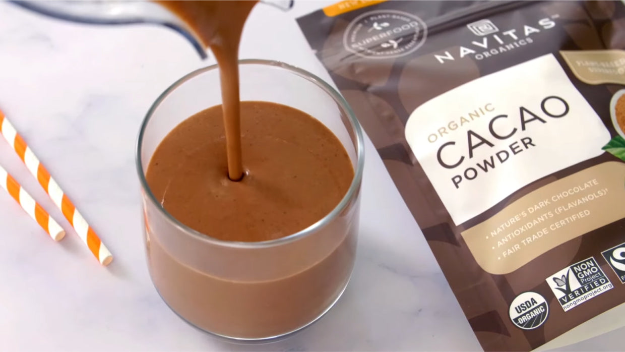 Bag of Cacao Powder and cup of hot chocolate on countertop.
